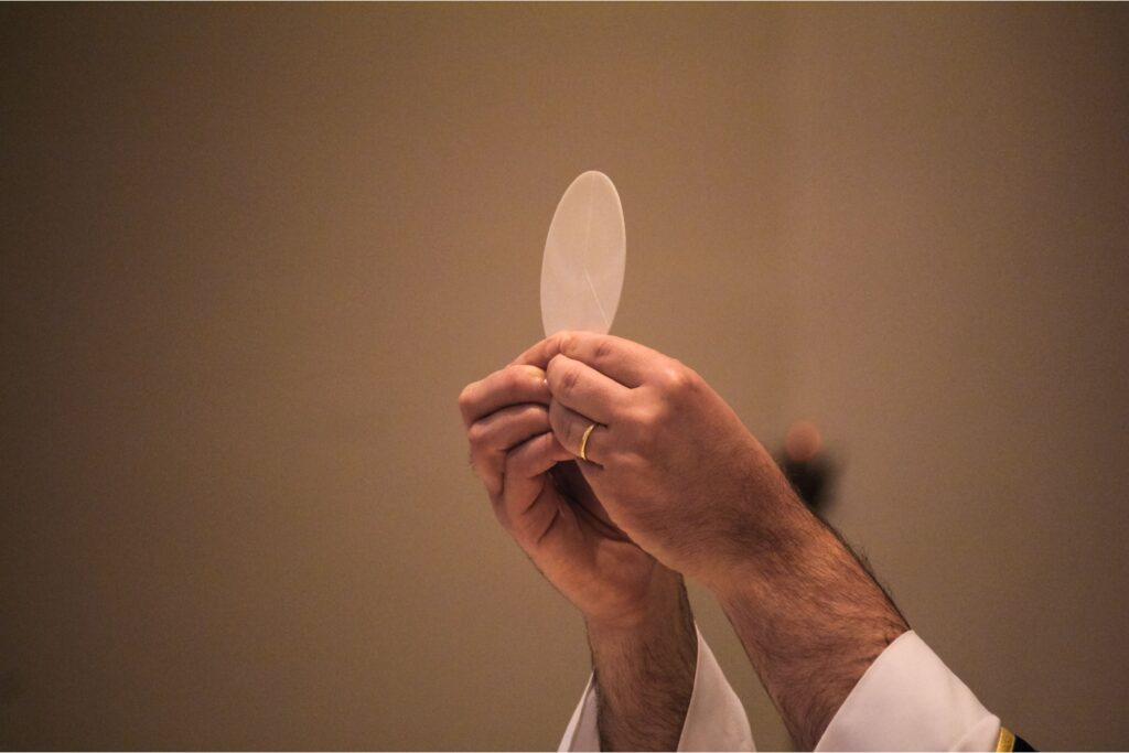 Catholic priest holding the Blessed Sacrament at mass, power of daily mass